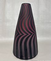 Side view of the conical vase showing red and black swirling stripes in a matte finish.