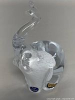 Clear art glass elephant figurine with trunk raised, displaying Made in Sweden and Mantorp Sweden stickers.