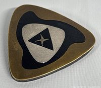 Front view of triangular modernist style brooch with bronze, black and silver geometric design.