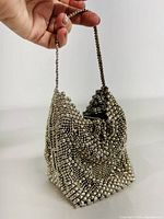 Front angled view of vintage metal mesh evening bag in liquid chrome finish showing shiny surface and chain handle.