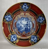 Front of the decorative plate showing Asian-inspired design with a red, blue, black, and gold color scheme, detailed patterns, and a central figure.