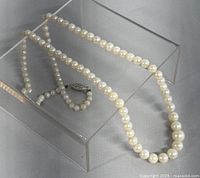 Full view of the pearl necklace displayed on a clear stand showing the strand and clasp.