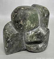 Front and angled views of the stone sculpture showing its textured surface and carved abstract features.