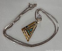 Photo showing the full 19 inch silver chain and triangular pendant with inlaid colored details.