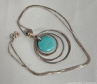 Full view of the silver necklace with turquoise pendant laid out flat showing chain and pendant details.
