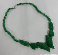 Full view of the necklace laid out showing the round jade beads and carved jade pendants.
