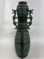 Front view of the vintage Japanese metal vase showing double dragon handles, relief designs on the body and neck, and square top.