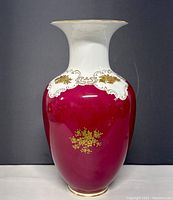 Front view of the white and deep red porcelain vase with gold floral detailing