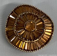 Front view of the vintage amber rhinestone brooch showing spiral design in gold-tone metal.