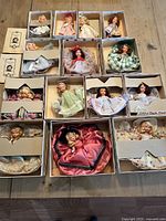 Overhead shot showing 14 boxed dolls arranged on wooden table