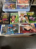 Full view of 7 VHS movies stacked including Disney titles and Robin Williams Flubber in original packaging.
