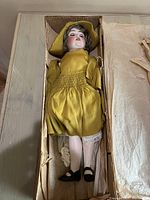 Full view of doll laid in box with lid open