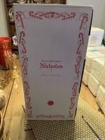 Outer decorated box of the doll showing "Nicholas" and Hamilton Collection branding with candy cane border.