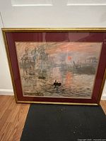 Photo of the full framed Monet print showing a harbor scene with boats, red sun, and acrylic frame.