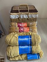 Vintage yarn skeins including Sayelle and Bear Brand Win-Knit yarns displayed in front of basket