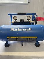 Front view of Mastercraft air compressor with brand logo and pressure gauges visible