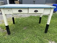 Front view of table showing metal top, two drawers and painted legs