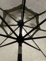 Close-up photo showing the black metal frame and ribs underneath the beige fabric canopy.