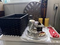Overall view of lot items on white platter showing basket, candles, and decorative items