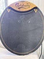 Front view of large oval Carlsberg branded chalkboard with wooden top section and gold decorative accents