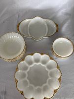 Full view of the white milk glass dish set showing the deviled egg plate, side bowls, and divided serving dish with gold trim.
