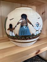 Side view of large rounded Tonala vase with painted traditional Mexican folk art scene showing a woman and children holding hands.