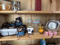 Shelf with unopened packets of McCafe coffee pods and various kitchen accessories including glassware, ceramic, and metal items.