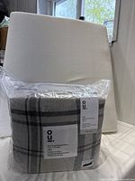 Packaged plaid flannel flannel sheet set in gray and white plaid pattern, made in Portugal, visible material and label.