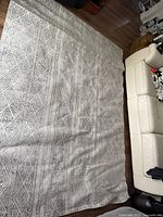 Full view of Turkish area rug spread on floor next to a cream leather sofa, showing overall pattern and size fitting 67x108 inches dimensions.