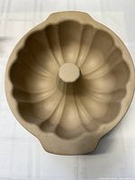 Top view showing the fluted design and central tube of the tan stoneware Bundt pan with two handles.