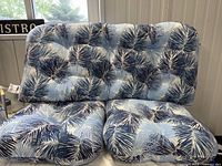 Full view of love seat cushions with blue palm leaf pattern on patio furniture