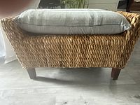 Side view of the wicker footstool showing weave texture and cushion on top