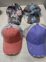 Top view of all four ponytail hats showing tie-dye and mesh back styles with velcro closures.