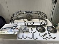 Full view of the pot hanger set laid out on a table including metal frame, hooks, chains, ceiling mounts, and boxed pull corkscrew kit.