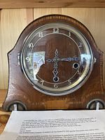 Front view of Smith Enfield Art Deco wooden mantel clock with visible wood grain, metal numerals and hands, and a closed glass face cover.