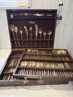 Full set displayed in open teak canteen showing various cutlery pieces organized in slots, stamped Thaipex logo visible