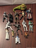Star Wars keychains laid on wooden surface showing full lot of 13 figures including Jabba the Hutt, Han Solo, Chewbacca, and others.