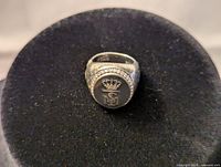 Front view of sterling silver men's ring with crowned TSM emblem and surrounding decorative border.