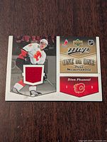 Front of Upper Deck MVP 2006-07 Dion Phaneuf hockey card with embedded red jersey swatch from Calgary Flames uniform.
