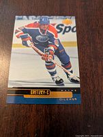 Front side of the 1999-00 Upper Deck Wayne Gretzky hockey card showing player in Oilers jersey skating with stick.