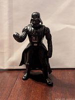 Front view of black Darth Vader Kenner Power of the Force Star Wars action figure standing with clenched fist and visible control panel painted on chest.