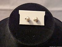 Front view of the women's pearl stud earrings showing white pearls on display card.
