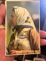 Close-up photo of a postcard featuring a woman in a patterned headscarf and beige cardigan