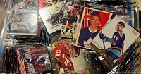 Collection of mixed condition 1990s ice hockey cards in loose pile, some cards feature images of players in uniforms with varied designs and colors.