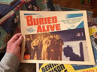 Color lobby card titled 'Buried Alive' with image of men in shadows and cast credits including Beverly Roberts and Robert Wilcox.