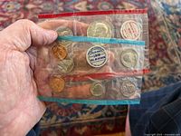 Photo of both 1968 US Mint uncirculated coin sets held in hand inside original cellophane packaging showing coins and Mint seals.