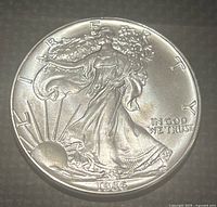 Obverse side of the 1986 American Silver Eagle coin showing Lady Liberty walking with the rising sun and inscriptions.