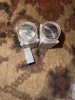Photo showing tops of two rolls of quarters, one 2004 Colorado and the other 2006 Nebraska, with design details visible.