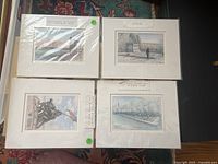 Four matted prints showing different US military memorials by Frank Morgan, laid out together under plastic covers on a flat surface.