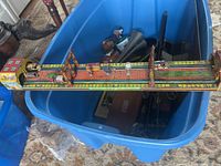 Full length view of the German wind-up terminal toy showing two small figures, a street clock, and architectural litho details on the surface.